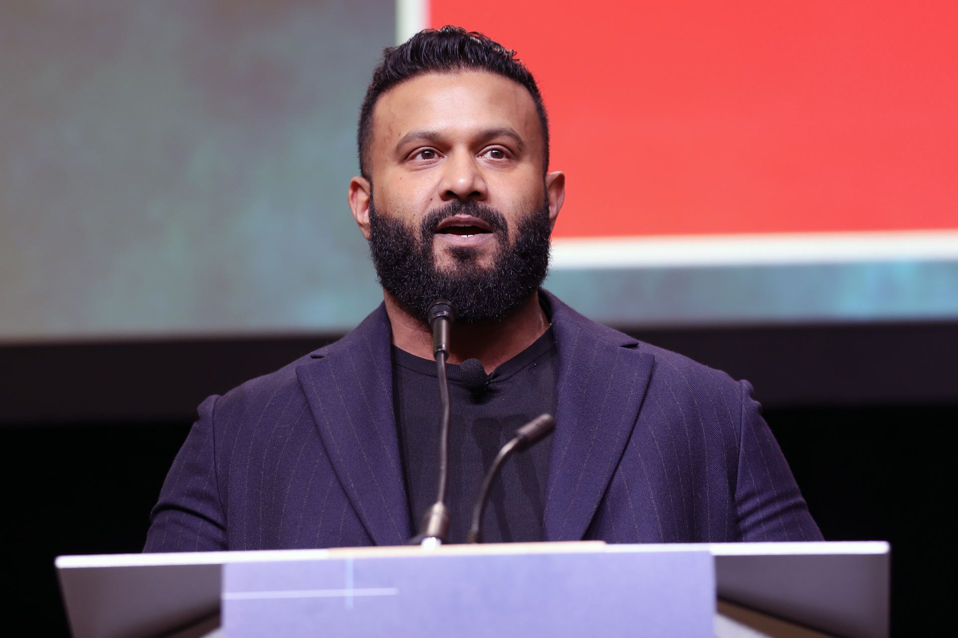 Dax Dasilva speaking at a podium during the IMPAC5 conference in Vancouver