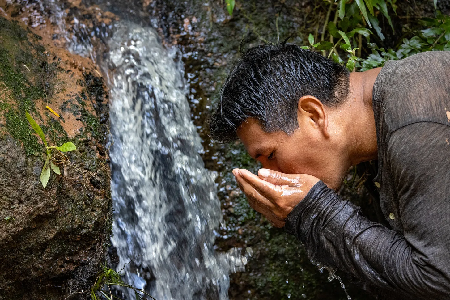 A hand meeting the surface of a clear river