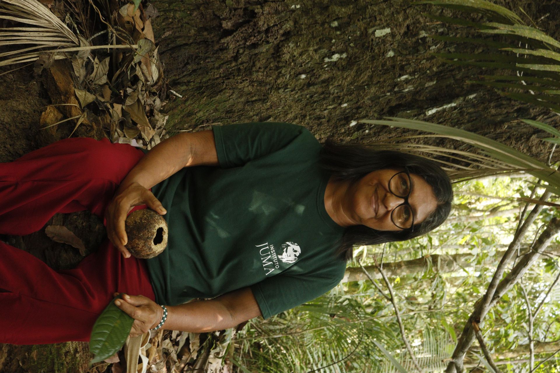A person with traditional face markings looking upward in a forest setting
