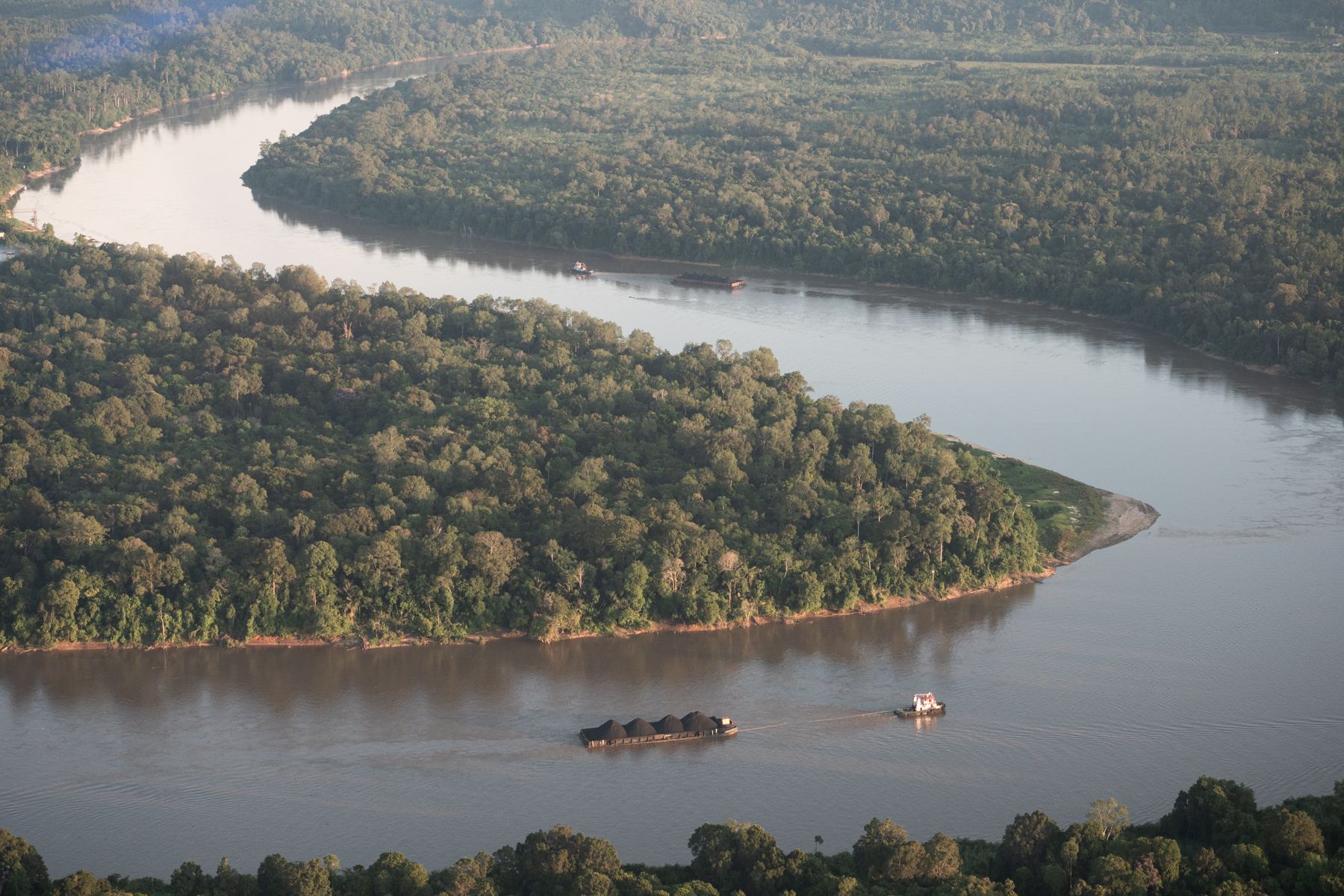 Aerial view of a wide river curving through tropical rainforest bordering the Dulan Forest Reserve in Borneo, Indonesia